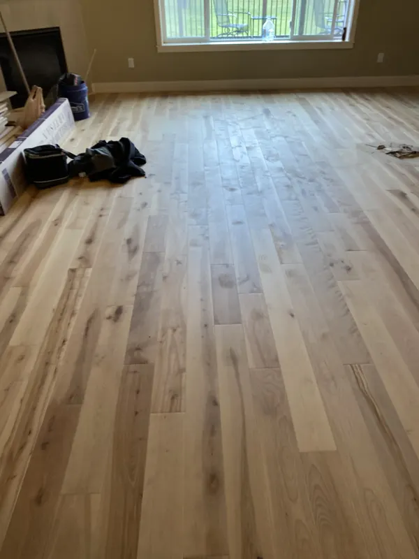 Pale white oak boards running the length of a bright empty room