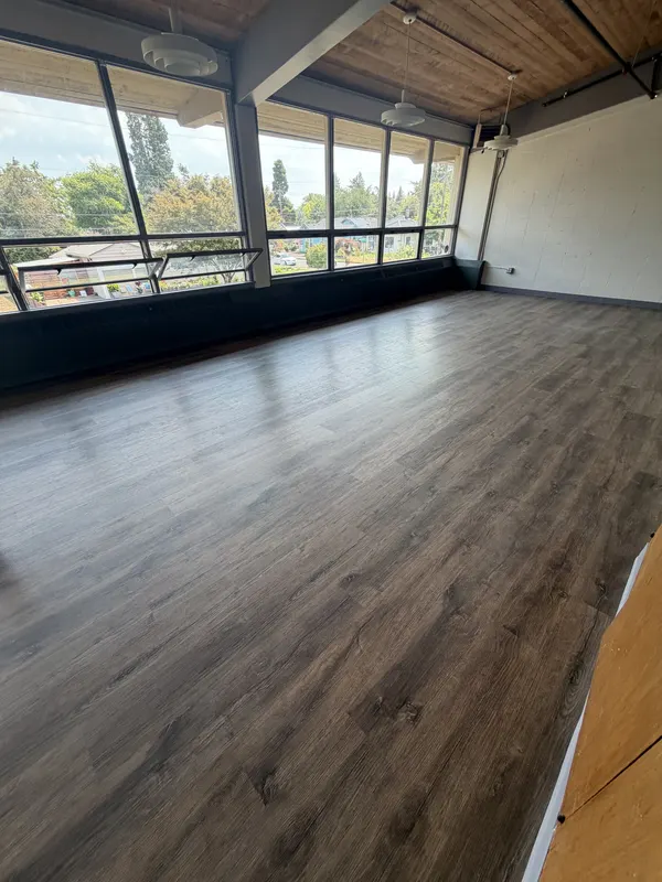 Grey plank floor under a beamed cedar ceiling with a wall of windows