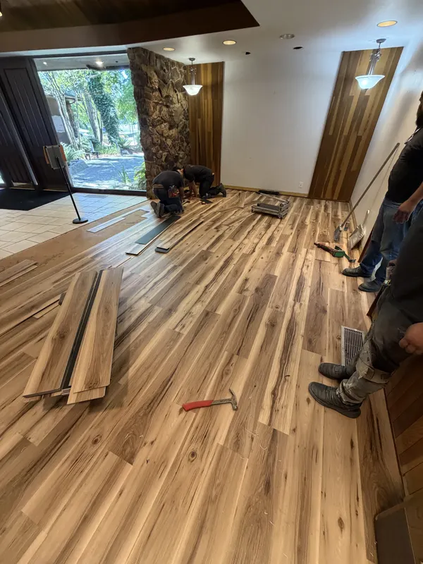 Two of the crew setting out planks across a room mid install