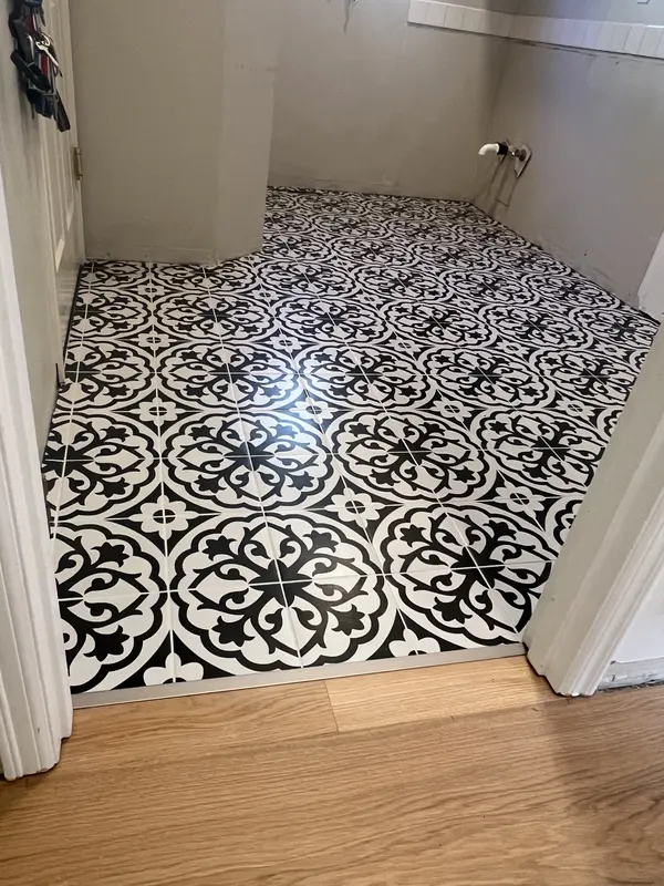 Patterned black and white vinyl tile fitted in a small bathroom