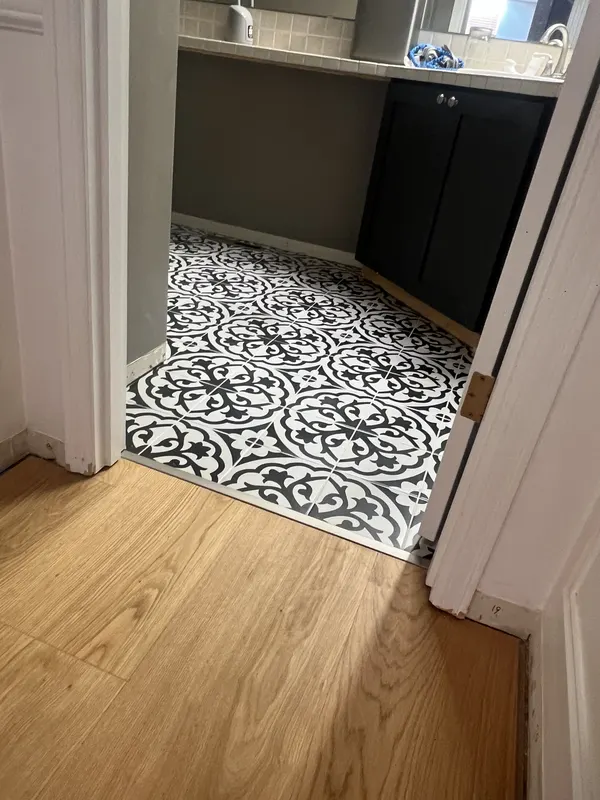 Patterned vinyl tile meeting plank flooring at a doorway