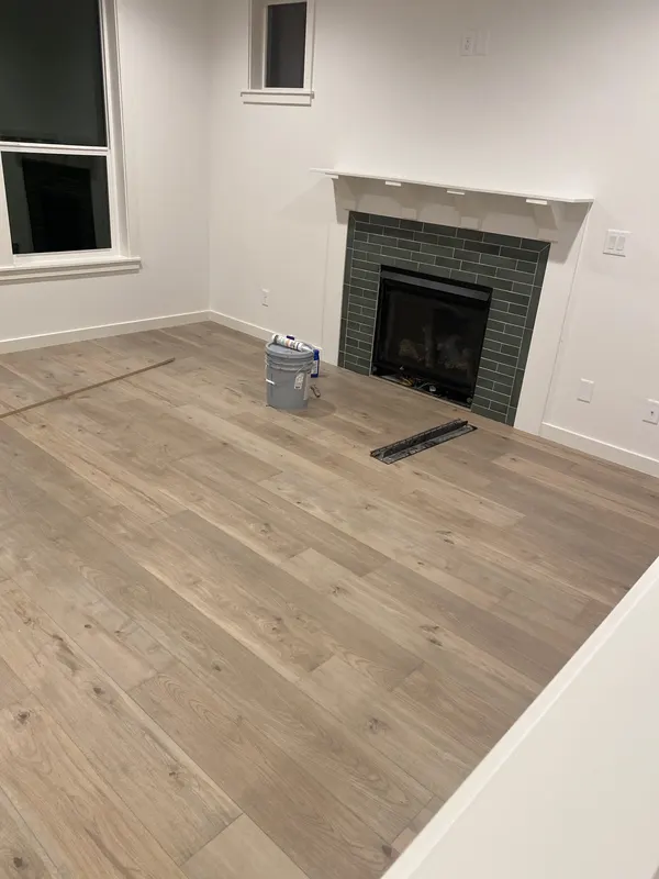 Pale oak floor running past a tiled fireplace in a new build