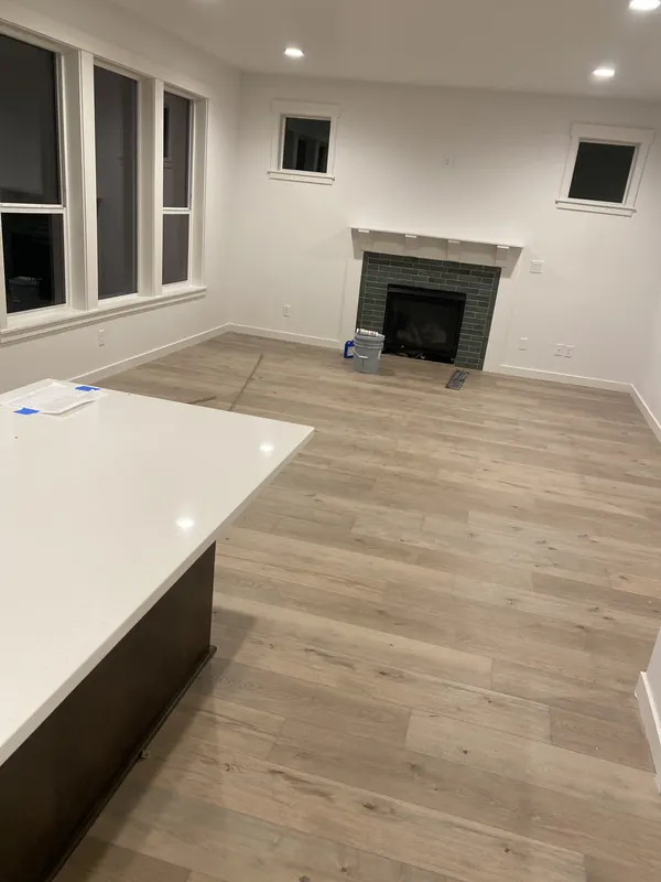 Pale oak floor beside a quartz topped island in a new kitchen